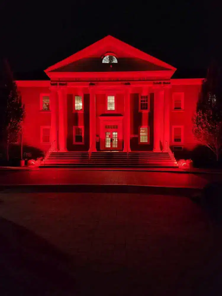 Historic building illuminated in vibrant red using RGB LED flood lights, showcasing dynamic color-changing architectural lighting for nighttime events and visual impact.